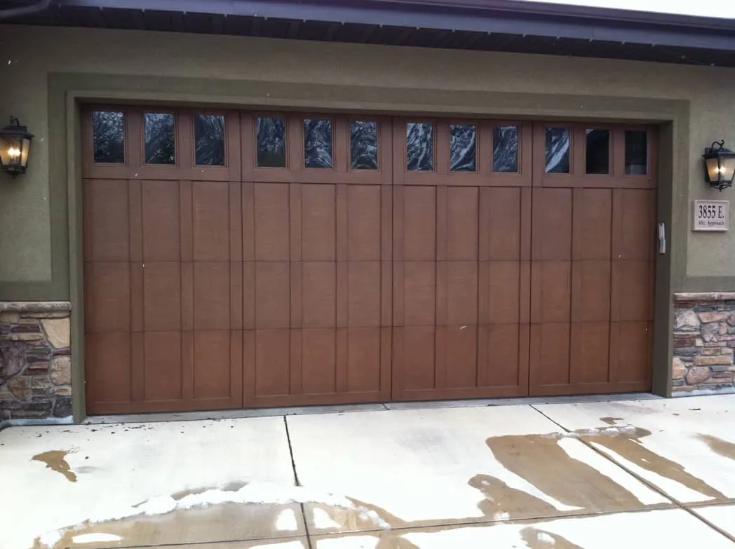 White Barn Style garage doors with windows and decorative black hardware on a residential home