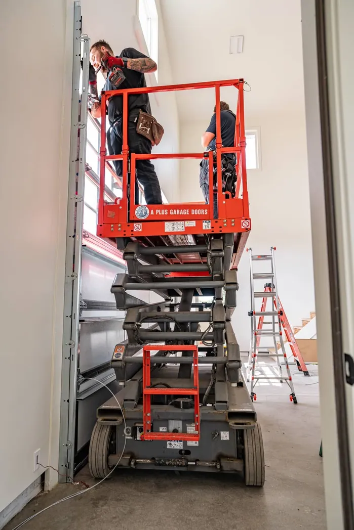 Commercial installation crew using scissor lift on garage door project