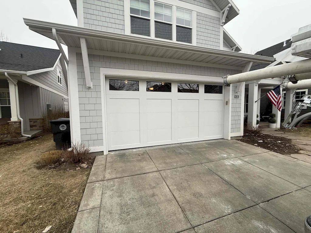 White residential garage door with windows and landscaped driveway